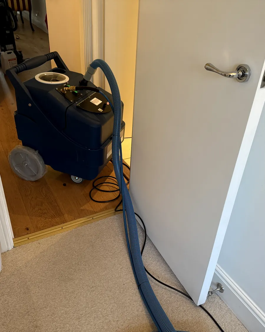 Extraction machine standing in a doorway with hose running through to the working area