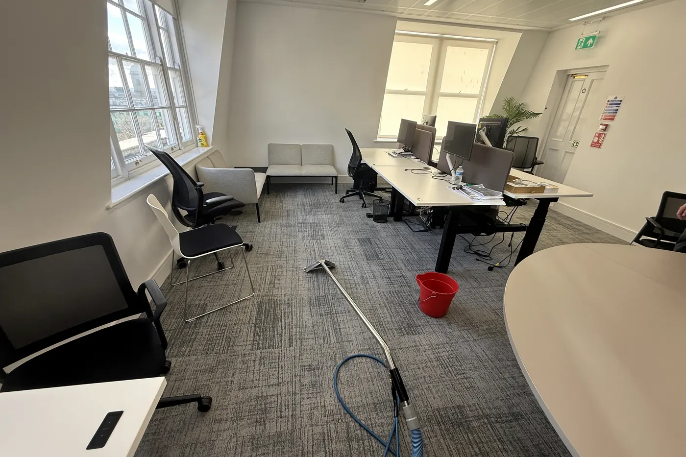 Extraction wand resting on an open-plan office floor between desks and chairs