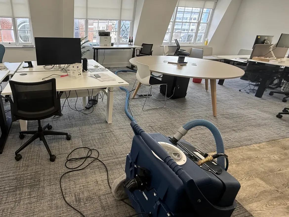 Extraction machine positioned on an open-plan office floor with hose run out between workstations